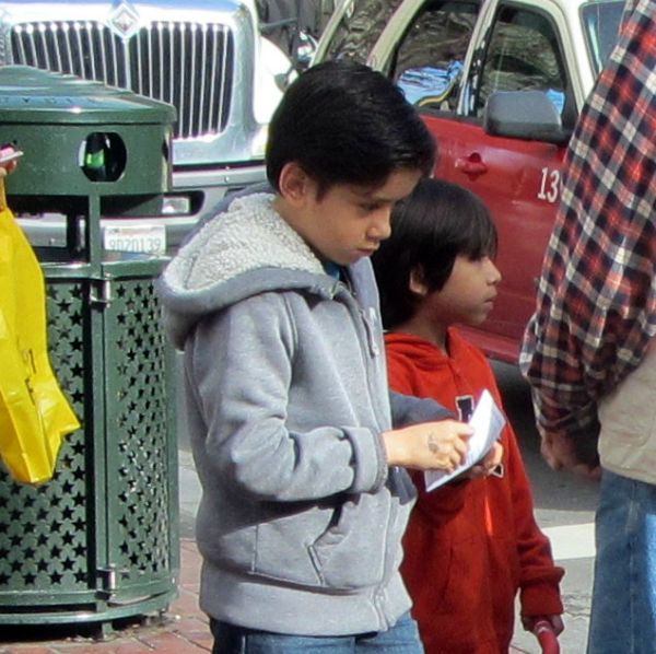 A BOY READS A TRACT AT 5TH ST AND MARKET.