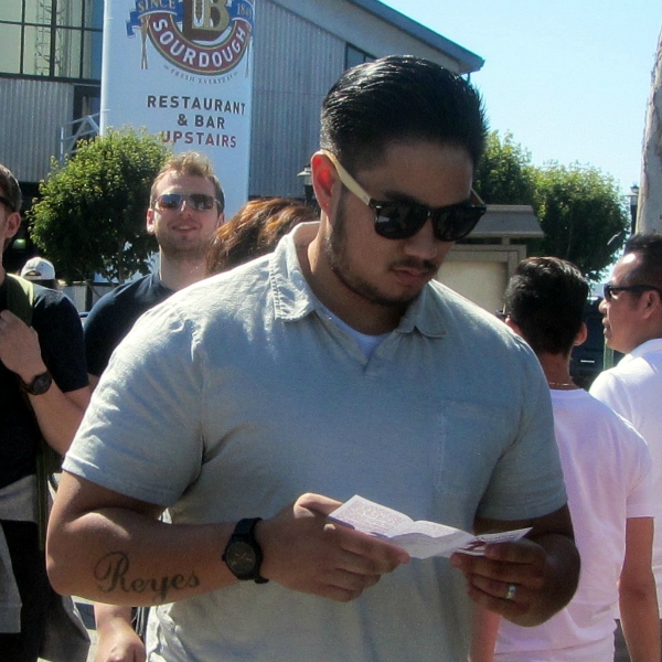 MAN READS TRACT AT FISHERMAN'S WHARF.